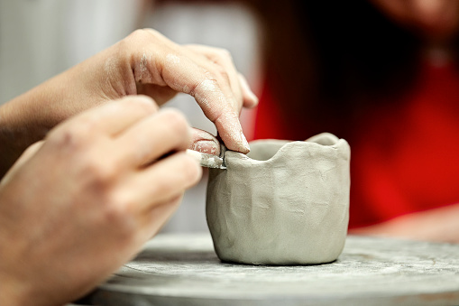 Artist's hands making cup with clay at studio