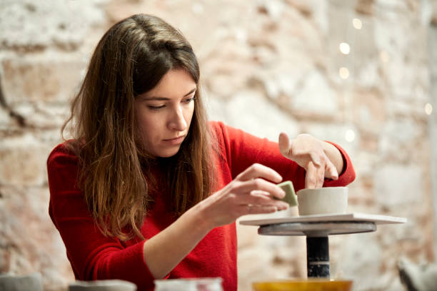 istock Woman molding clay with sponge at workshop 939572070