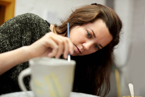 istock Woman painting clay cup in studio 939572206