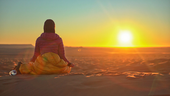 Lone woman enjoying desert sunset from the top of dune