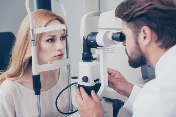 istock Concentrated brunet bearded optician with non contact tonometer is checking blond`s lady patient intraocular pressure at eye clinic. Health care, medicine, eye sight and technology concept 939577258