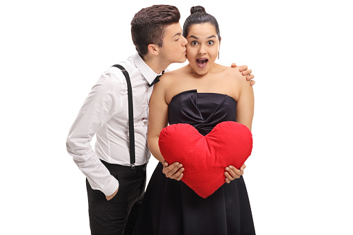 Elegantly dressed teenage boy kissing his girlfriend isolated on white background