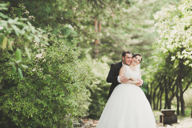 istock Newly married couple running and jumping in park while holding hands 939579606