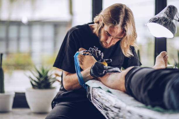 istock Artist making tattoo on man's leg 939581942