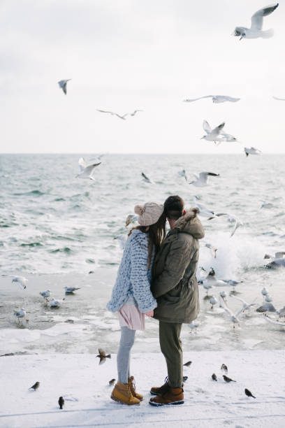 istock young couple holding hands on seashore and looking on seagulls 939585014