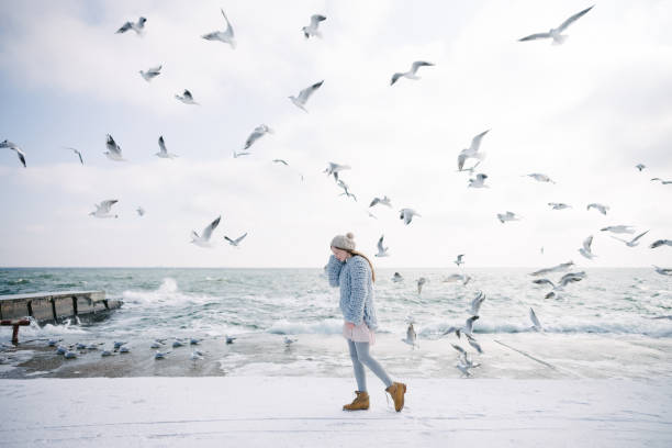 istock stylish young girl on winter seashore with seagulls 939585264