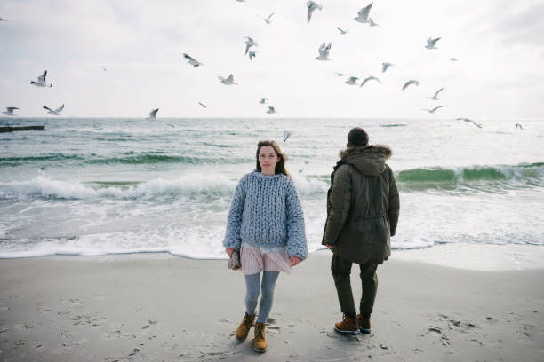 istock young couple standing on winter sea shore with seagulls 939585744