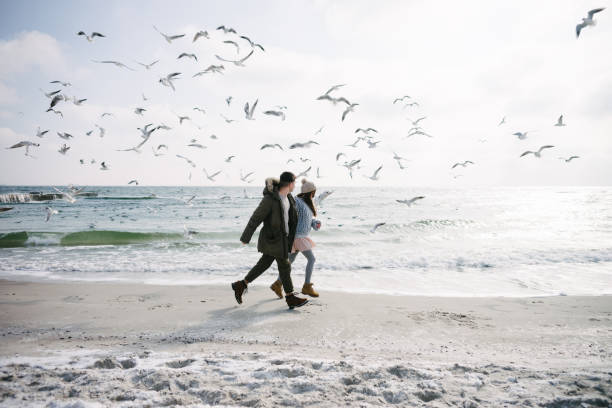 istock young couple running on winter sea shore with seagulls 939587018