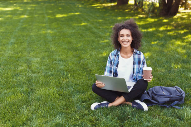 istock Happy young black woman using laptop in park 939587096
