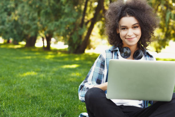 istock Happy young black woman using laptop in park 939587108