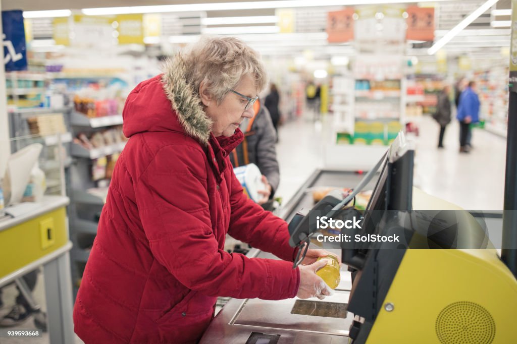 Haute femme à l’aide de caisse de libre-service - Photo de Passage en caisse libre de droits