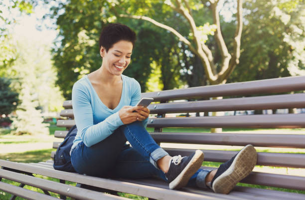 istock Smiling woman typing on mobile outdoors 939597944