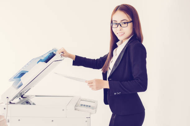 istock Smiling Asian Business Woman Using Copier Machine 939600602