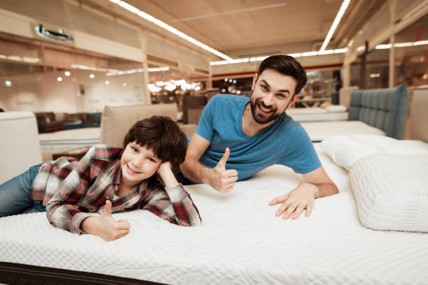 istock Handsome bearded father with young son is testing mattress for softness. 939600696