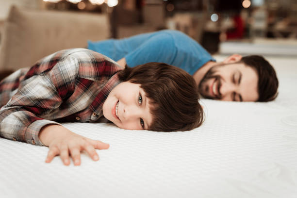 istock Handsome bearded father with young son is testing mattress for softness. 939601736