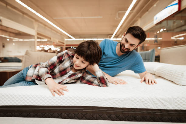 istock Handsome bearded father with young son is testing mattress for softness. 939606284