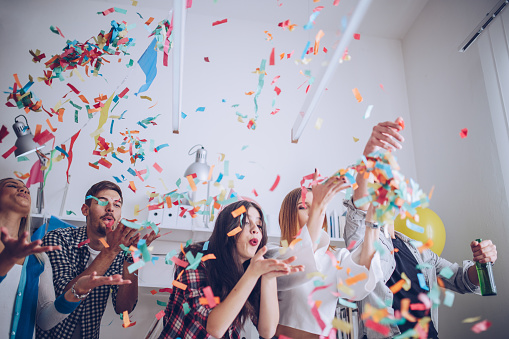 Group of young colleagues celebrating birthday party in modern office