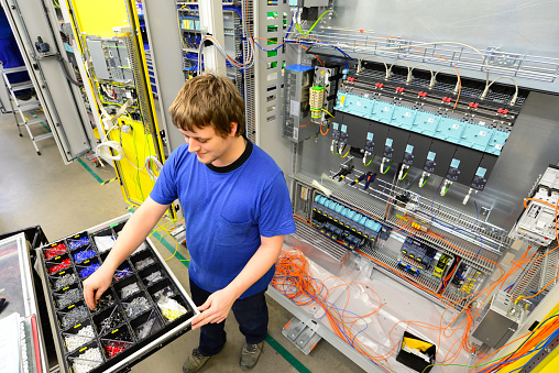 operator assembles machine in a factory - production of switch cabinets for industrial plant