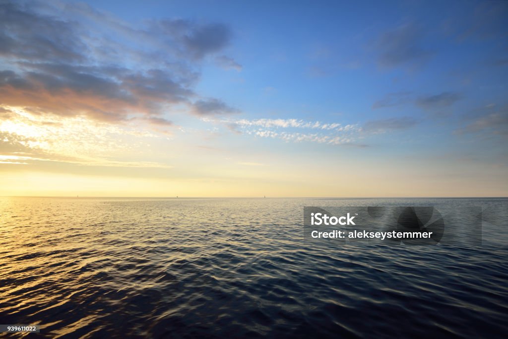 Sunset in a cloudy sky over open Baltic sea with veri distant ship silhouettes. Sea Stock Photo