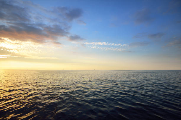sunset in a cloudy sky over open baltic sea with veri distant ship silhouettes. - nobody horizontal seascape landscape imagens e fotografias de stock