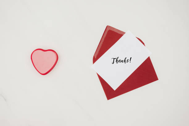 istock top view of red envelope with THANKS lettering on paper and heart shaped box isolated on white 939626708