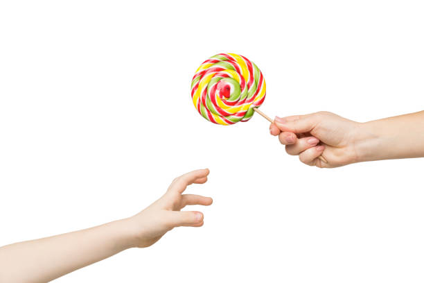 mano del bambino che cerca un grande lecca-lecca colorato - lollipop isolated multi colored candy foto e immagini stock
