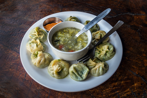 Nepalese traditional dumpling momos served with tomato chatni and hot soup