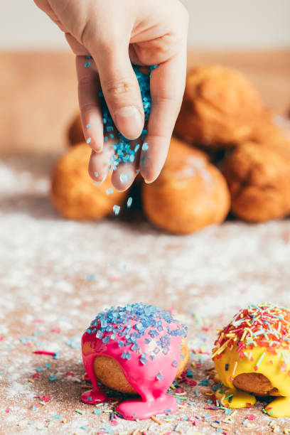 istock Woman sprinkling sugar strands on doughnuts 939658714