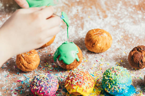istock Woman's hand coating a donut with green frosting. 939658720