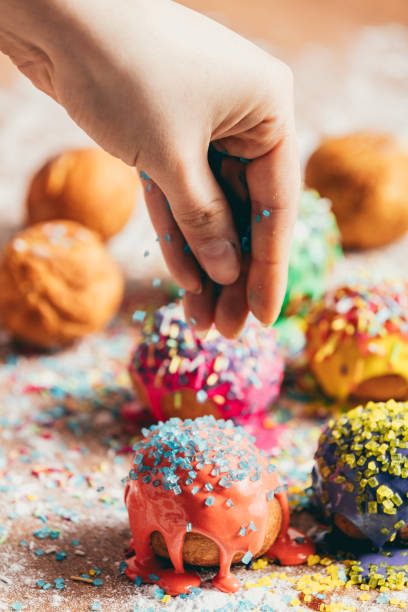 Doughnuts sprinkled by a woman with sugar sprinkles.