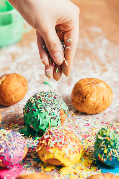 istock Woman sprinkling sugar strands on doughnuts 939658750