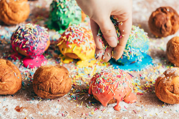 istock Woman sprinkling sugar sprinkles on donuts 939658754