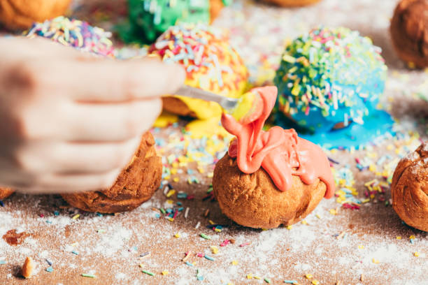 istock Woman pouring orange frosting on a doughnut. 939658756