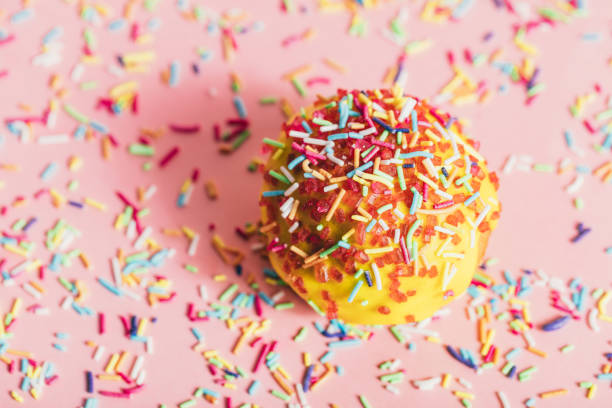 istock Sprinkled yellow doughnut on pink background. 939658796