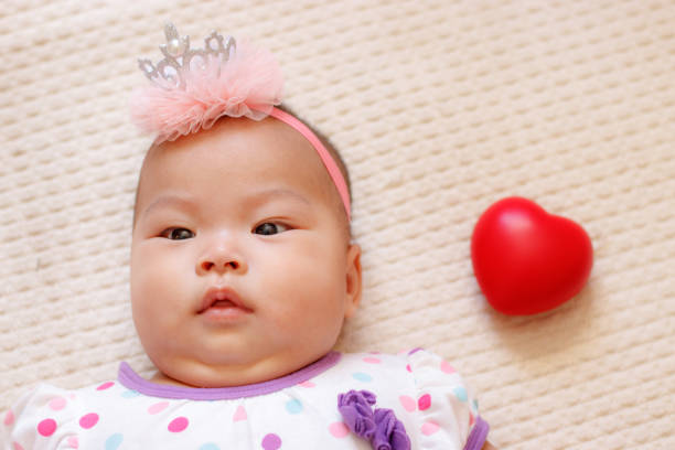 jolie fille asiatique nouveau-né avec coeur rouge. - baby yawning asian ethnicity newborn photos et images de collection