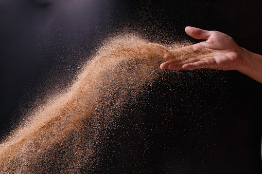 sand explosion with right hand on black background