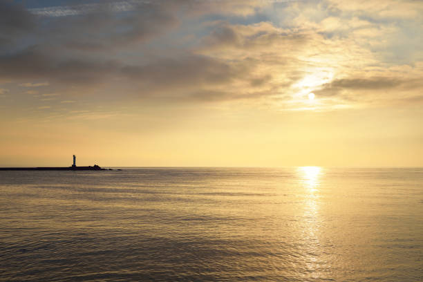 istock Horizontal image of a distant lighthouse silhouette on a stone pier on daugava river in Riga at sunset 939679586