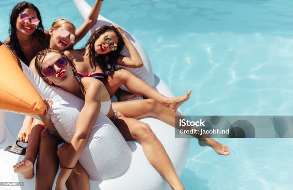 Femmes flottant ensemble sur un gros jouet gonflable de piscine - Photo de Piscine libre de droits