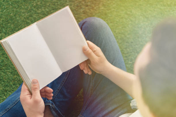 istock cropped shot of young man reading book while sitting on grass 939687588