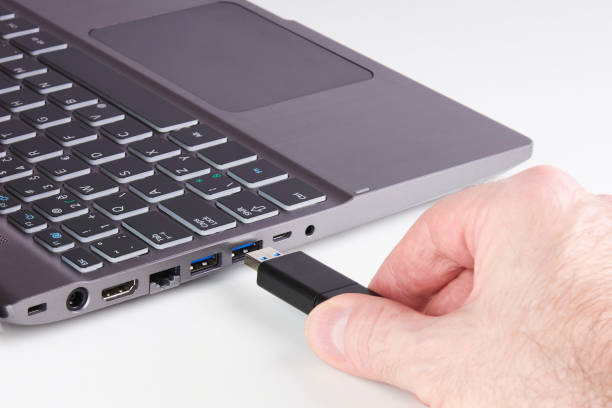istock Silver laptop and male hand holding USB Flash disk and plugging into slot - on white background 939688116