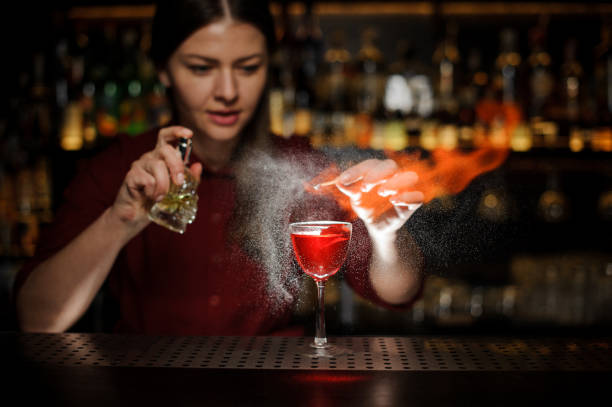 istock Female bartender spraying on a fire match above the cocktail 939693360