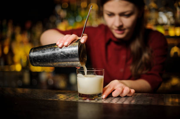 istock Female bartender pouring out a white cocktail from the shaker 939693518