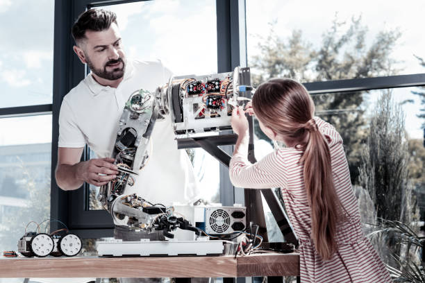 istock Smart girl helping her teacher with robotic machine 939695406