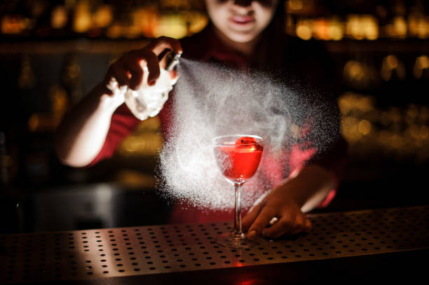 istock Female bartender spraying on the red cocktail for serving it 939695568