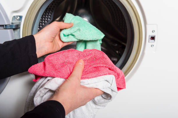 istock woman louding laundry into washing machine 939696756