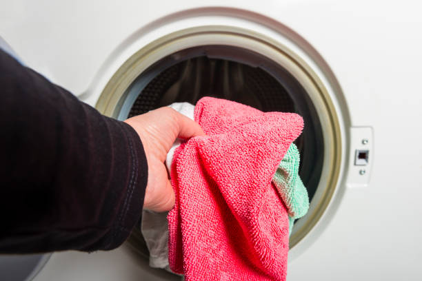 istock woman louding laundry into washing machine 939697922