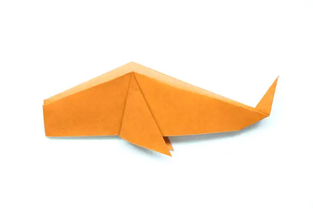 Photo of Orange origami paper in fish or whale shape on white background
