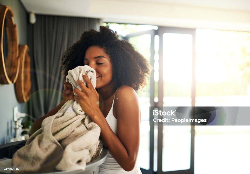 So clean and so fresh, exactly how I like it Cropped shot of an attractive young woman smelling clean laundry at home Laundry Stock Photo