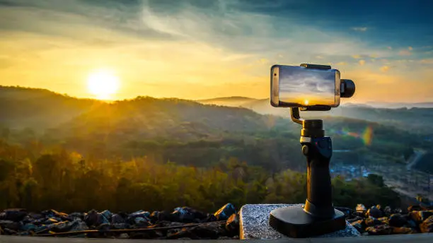 Close-up Smartphone take a Mountians Landscape photo and video timelapse on stand Mobile Stabilizer in sunset