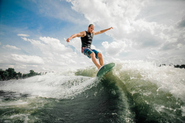 istock Young and active man wakesurfing on the board down the river 939715224